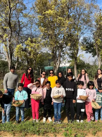 A group photo of families and children after a successful vegetable picking session, with everyone holding their baskets of fresh produce.
