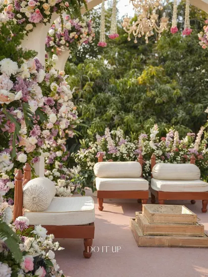 The traditional low seating, or 'baithak', inside the mandap, surrounded by dense floral arrangements. The design ensures that even the most traditional elements feel fresh and beautifully styled.