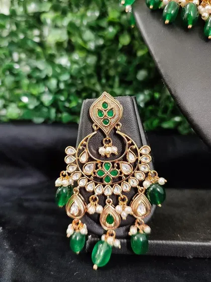 A close-up of a chandbali earring with green enamel and kundan work. This rental piece is part of a larger set but is stunning on its own.