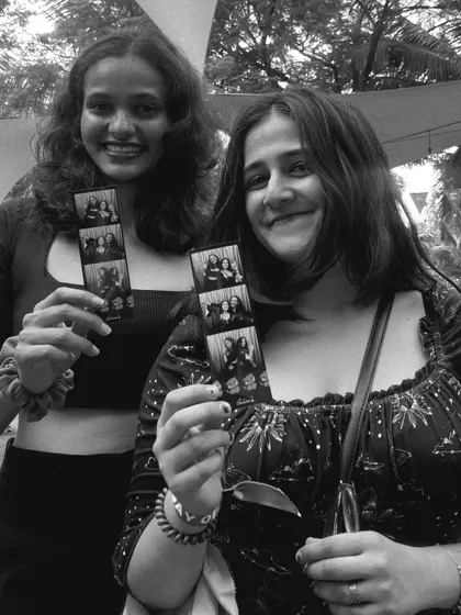 Two happy students holding up their photo strips. My booth is all about creating these small, tangible pieces of happiness.
