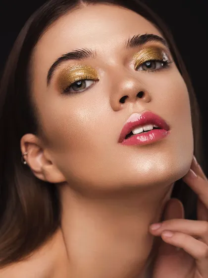 A glamorous beauty shot featuring metallic gold eyeshadow and glossy pink lips. This look, created by MUA Shreya Chadha, is a perfect example of a bold, high-impact makeup application that we love to capture.