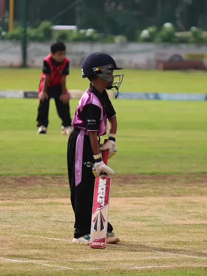 A young batter waits patiently for the bowler, demonstrating good temperament at the crease.