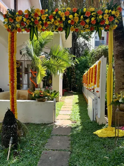 A beautiful floral archway made with marigolds and other traditional flowers to welcome guests to an outdoor ceremony.