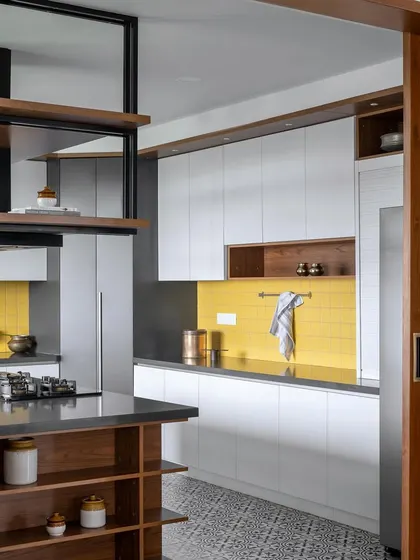 A side view of the 'Vasudhalayah' kitchen, highlighting the custom-designed overhead unit above the island, which incorporates an extractor hood and shelving.
