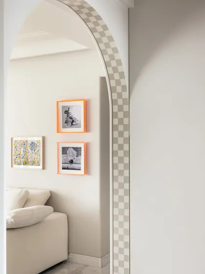 Details matter. The checkered pattern on the archway and the bright orange frames add a playful touch to this corner, reflecting the home's artistic and joyful design.