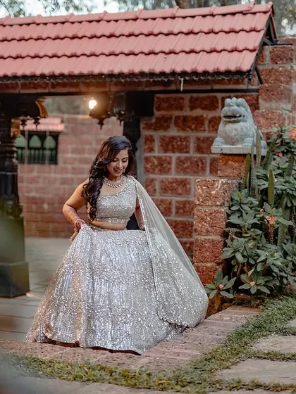 An elegant portrait of the bride, Ashwini, amidst the lush greenery and traditional architecture of her reception venue.