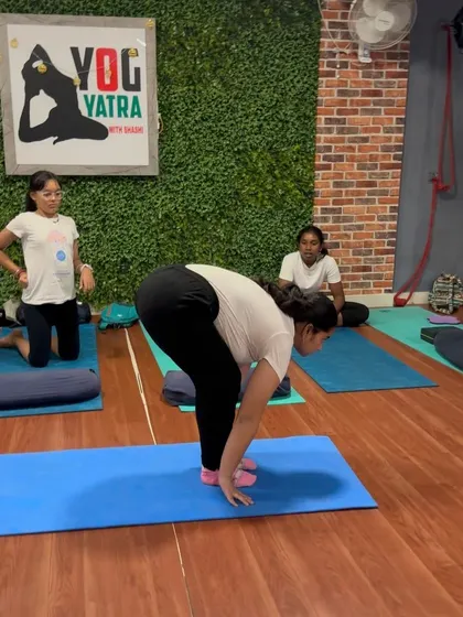 A student practices Ardha Uttanasana (Half Forward Bend), focusing on creating a long, flat spine before folding forward.