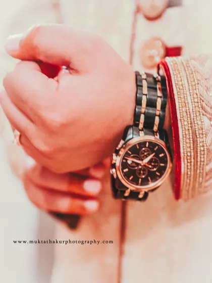 The groom adjusts his watch, a classic getting-ready shot that captures a moment of quiet preparation.