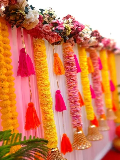 A close-up of a decor panel featuring marigold garlands, colorful tassels, and hanging bells. These small, traditional details come together to create a rich and festive texture.