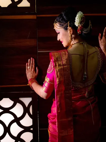 An elegant portrait of the bride, showcasing the beautiful design of her saree blouse from the back.