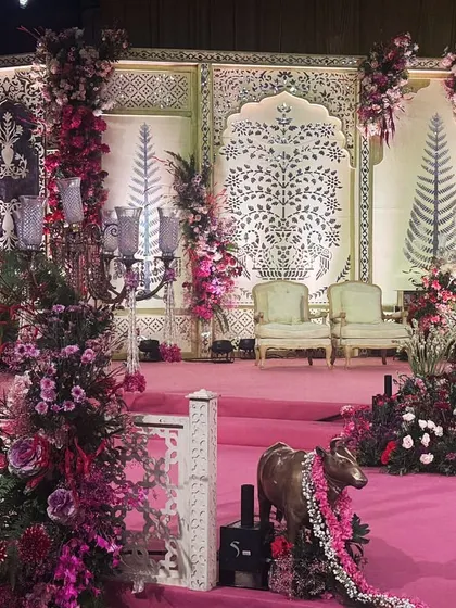 Another view of the pink-hued stage, showing how the floral arrangements frame the seating area and create a sense of depth and romance.