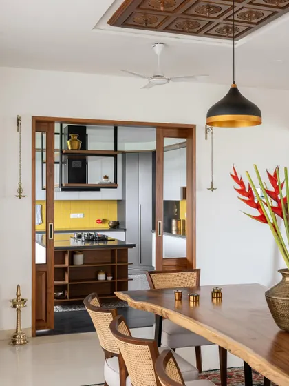 The 'Vasudhalayah' kitchen as seen from the dining area, framed by elegant wood and glass sliding doors that allow for both openness and privacy.