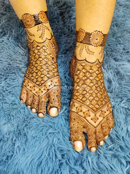 This bridal leg design features a heavy 'jaal' or net pattern across the foot, with a simple floral band at the ankle. It's a classic and beautiful choice.
