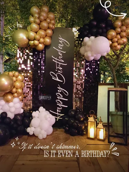 If it doesn't shimmer, is it even a birthday? This detailed shot shows our black sequin wall with custom calligraphy, framed by dramatic gold, black, and white balloon clusters and rustic lanterns.