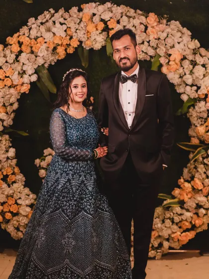 The happy couple posing against a beautiful floral arch. Her reception makeup was designed to be radiant and photo-ready, ensuring she looked flawless from every angle.