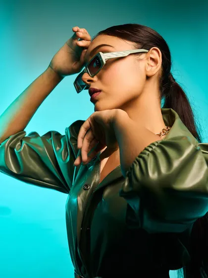 A high-fashion look featuring a green leather jacket and statement sunglasses. I used a vibrant aqua-colored background to make the olive green pop, creating a modern and edgy fashion portrait.