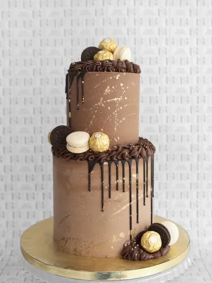 A two-tiered chocolate delight. This drip cake is adorned with macarons, Oreos, and Ferrero Rocher for a truly decadent experience.