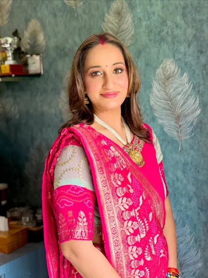 A beautiful look for a married woman, featuring a classic sindhoor, glowing skin, and a vibrant pink bandhini saree.