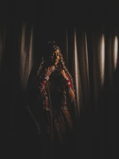 A dramatic, low-key shot of a bride, almost a silhouette, creating a sense of mystery and elegance.