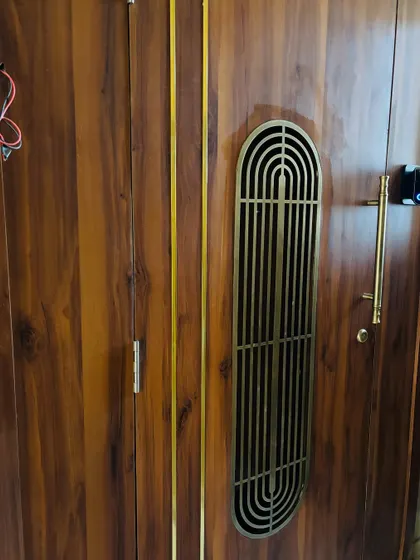 A work-in-progress shot of the grand wooden entrance, showing the beautiful brass grill and handle details before the final wiring is concealed.