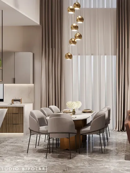 The dining area is defined by a cascade of golden pendant lights that hang from the double-height ceiling, creating a dramatic and elegant focal point over the marble-topped table.