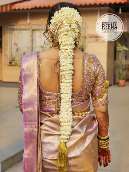 The back view of Nidhi's hairstyle, showcasing a traditional South Indian braid adorned with a full length of fresh jasmine flowers (mallige) and a beautiful hair accessory.