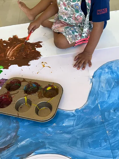 Getting hands-on with paint during a large-scale floor painting activity. We provide large canvases and plenty of space for kids to freely explore color mixing and application without worrying about making a mess.