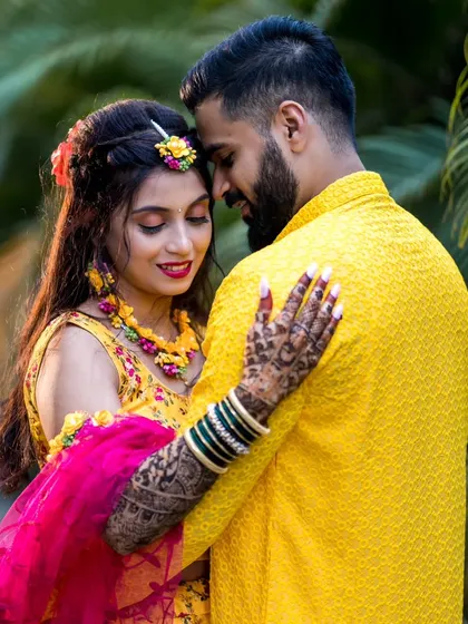 An intimate portrait of the couple in their vibrant Haldi outfits, sharing a quiet moment together amidst the greenery.