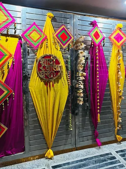The entrance gate of the wedding house, decorated with yellow and pink drapes and traditional Rajasthani hangings.