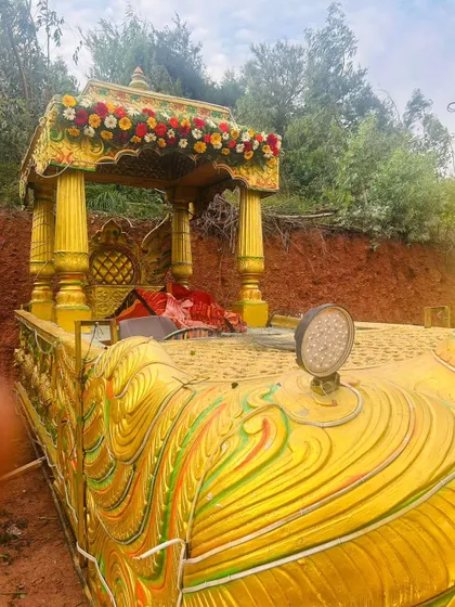 The back of a golden procession chariot, showing the ornate canopy decorated with fresh flowers.
