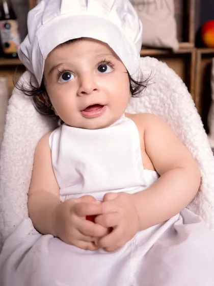 A delightful close-up of our little chef, capturing a moment of curiosity and wonder. These expressive shots are a beautiful part of any themed baby photoshoot.