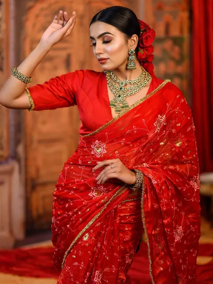 A beautiful portrait in a red embroidered saree. The addition of red roses in the hair adds a touch of romance and classic elegance to the look.