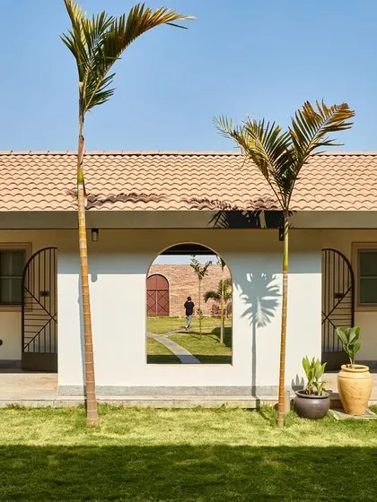The guest suites at Samavana are arranged around a central lawn, offering a serene retreat from the main festivities. An arched opening in the wall frames a view through to the other side, creating layers of space and visual connection.