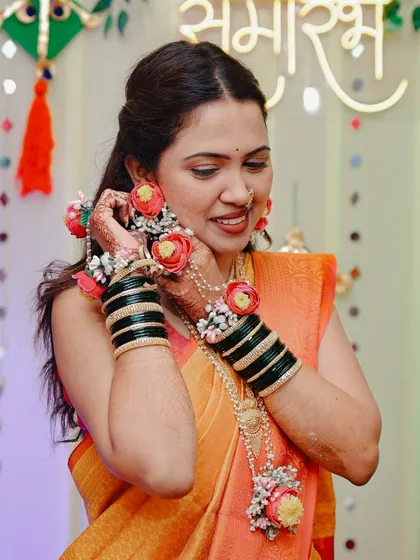 The bride adjusting her floral earring during her Haldi ceremony.