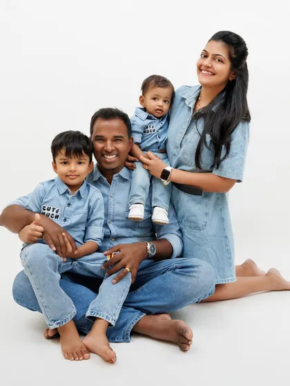 A happy family of four, all dressed in denim, posing together for a classic and joyful studio portrait.