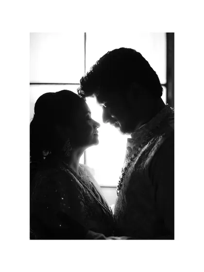 A romantic silhouette of a couple against a window, their faces close in an intimate moment.