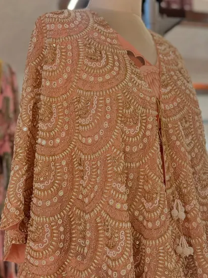 A detailed shot of a heavily beaded and sequined capelet in a beautiful scalloped pattern, a true work of art.