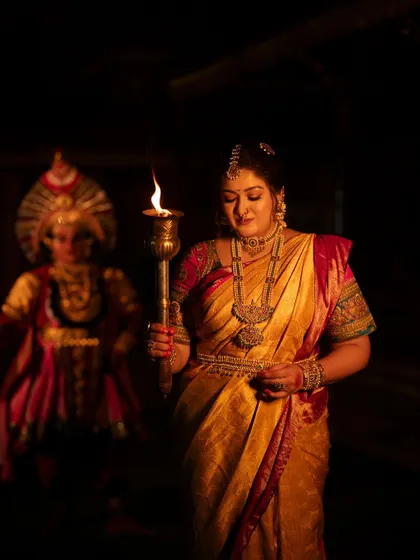 Meghana Raj with a gentle smile, holding the torch. This photo beautifully captures the concept of bringing light and courage.