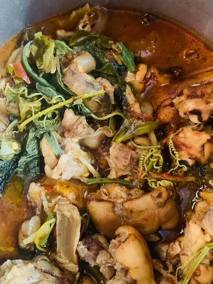 A pot of pig trotters cooked with tender pumpkin shoots.
