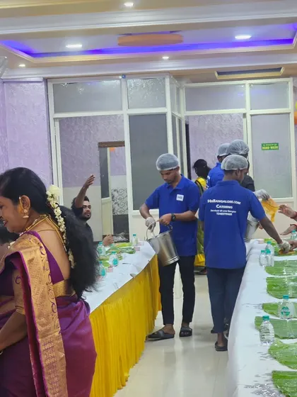 Our staff member in a blue HB uniform and hairnet serving guests with a smile during a wedding event.