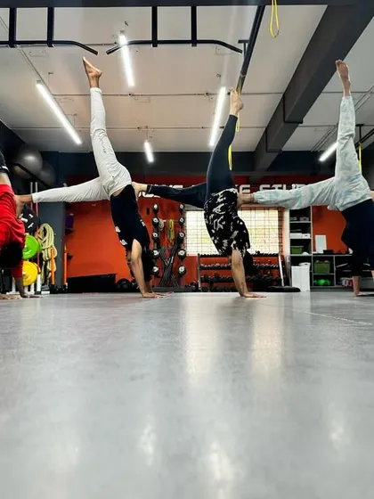 A fun and challenging group pose after a workout. This wall-assisted handstand requires core strength, balance, and teamwork.