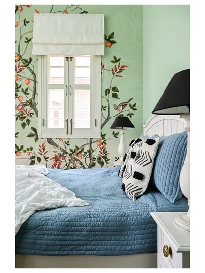 A cozy corner in the daughter's room, with a hand-painted mural of birds and branches, creating a whimsical, garden-like feel.