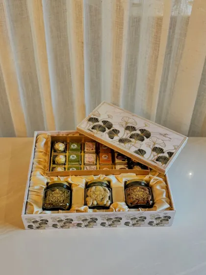 This exquisite hamper, featuring a delicate ginkgo leaf design, is a sophisticated choice for corporate gifting. This version includes three jars of premium dry fruits and a box of assorted sweets.