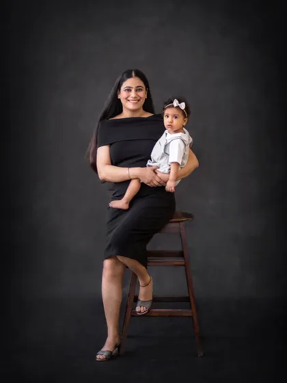 An elegant portrait of a mother and her baby girl. The simple black dress and dark background create a timeless and sophisticated look.