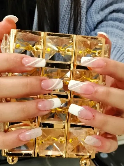 I love creating modern twists on classic styles. This look features a soft, natural base with a clean white tip and a delicate silver glitter swirl for an elegant finish. It is a beautiful example of a custom French manicure on nail extensions.
