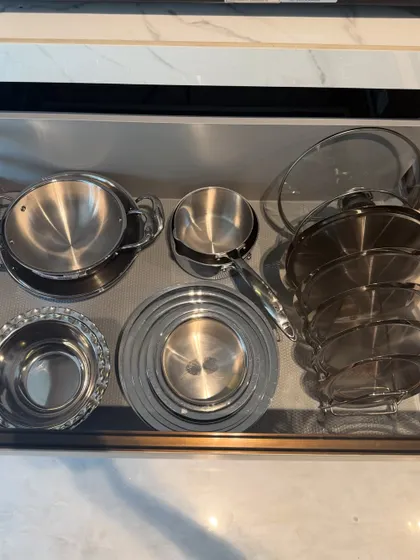 A drawer containing steel serving dishes and pots. By grouping similar items together, we create a clean, organized look that is easy to maintain.