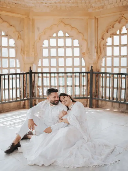 A serene moment of the couple sitting together inside a beautifully lit chamber in Amer Fort, capturing a feeling of peace and intimacy.
