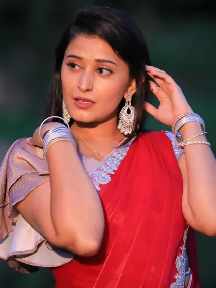A close-up shot showing the elegant earrings and the simple beauty of the red saree.