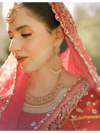A close-up portrait of the bride Ganeemat, focusing on her flawless makeup and traditional jewelry. The soft, natural light gives her a radiant glow on her wedding day.