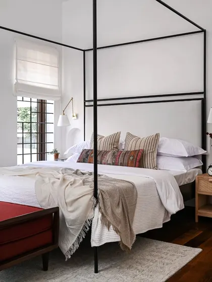 A master bedroom should be a sanctuary. I designed this serene space around a custom four-poster bed to create a sense of retreat. By adding a new wall with an arched doorway, I was able to carve out a spacious walk-in closet without sacrificing the room's open, airy feel.
